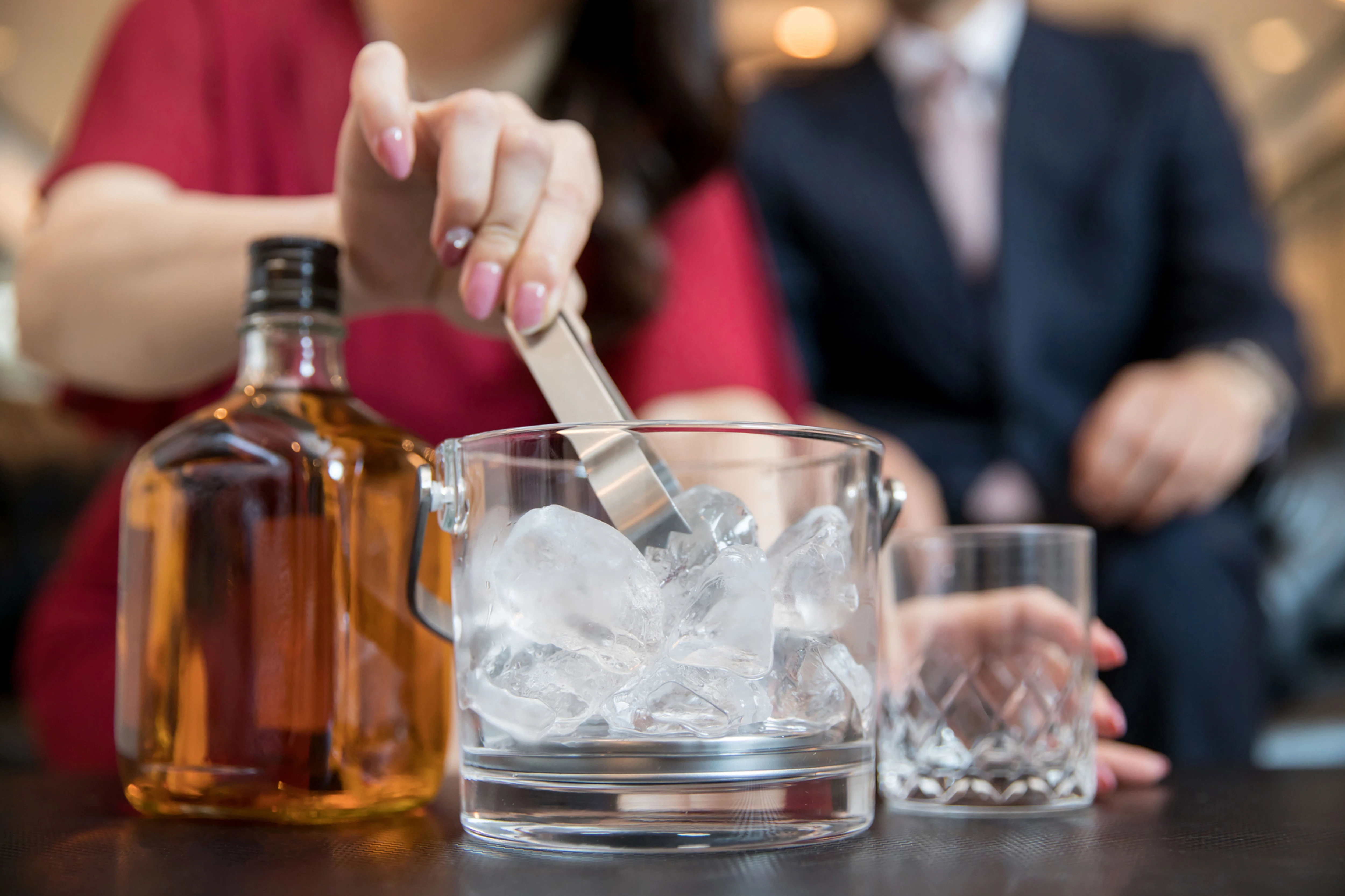Woman stirs ice in a whiskey glass